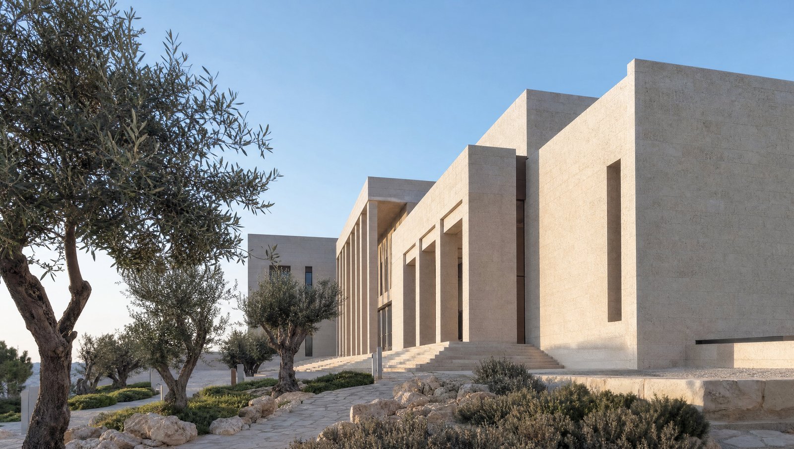 חזית בניין בית משפט מאבן ירושלמית בהירה ועצי זית באור בוקר